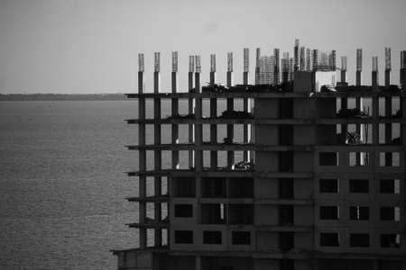 Apartment building construction process, ocean beach side, in black and white monochrome photoの写真素材
