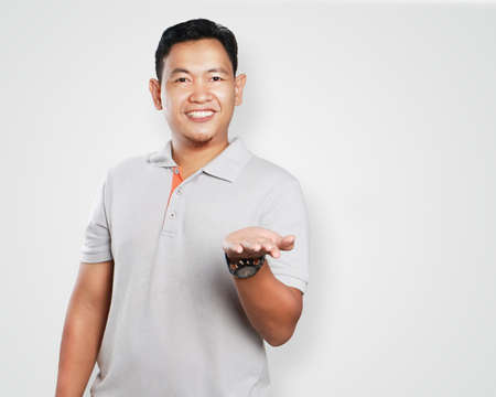 Photo image portrait of a cute handsome young Asian man smiling and showing his left palm open
