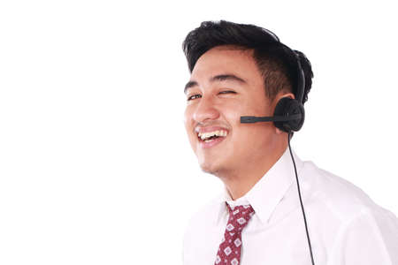 Photo image portrait of a cute young Asian male call center operator with headset on his head isolated on whiteの写真素材
