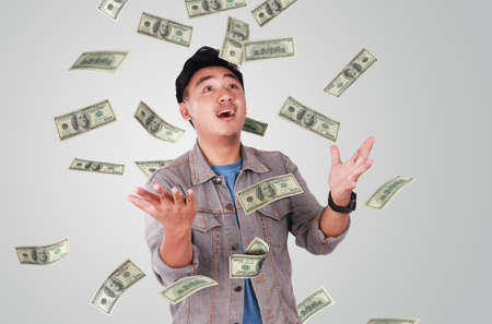 Photo image portrait of a cute young successful Asian male under rain of moneyの写真素材