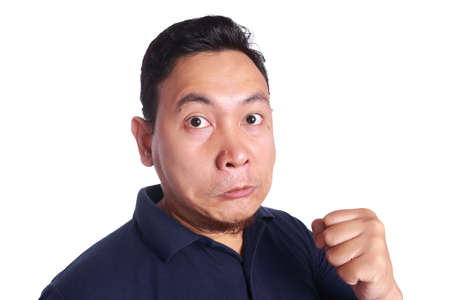 Photo image of funny Asian man showing synical unhappy angry mad punching fighting facial expression, isolated on whiteの写真素材
