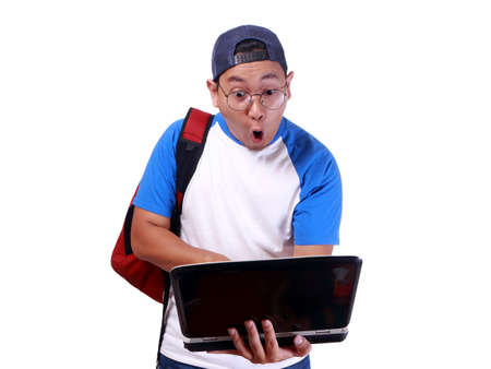 Portrait of young funny Asian student smiling and shocked while looking his laptop