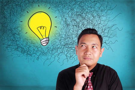 Portrait of young attractive Asian businessman thinking bright idea, problem and solution concept,...
