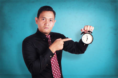 Portrait of angry businessman business manager boss showing alarm clock, mad of his too late employeeの写真素材