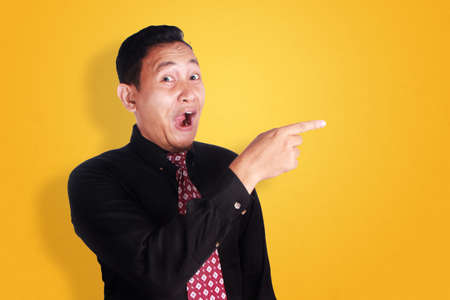 Portrait of happy young Asian businessman smiling and pointing to his side, successful business people conceptの写真素材