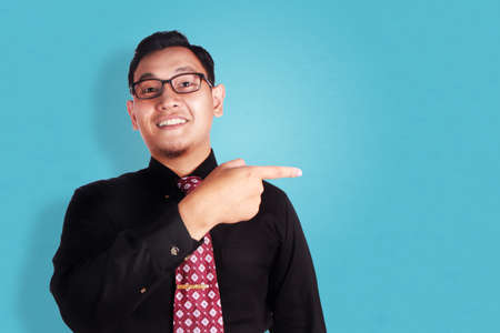Portrait of happy young Asian businessman smiling and pointing to his side, successful business people conceptの写真素材