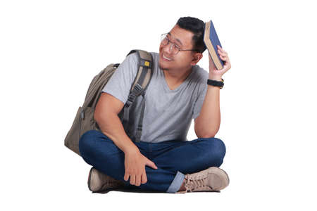 Attractive young Asian student reading book while sitting on the floor, isolated on white, sad regret failure gestureの写真素材