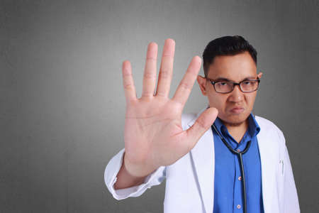 A Young Asian Doctor making stop sign over textured background,  portrait rude frustrated upset,...