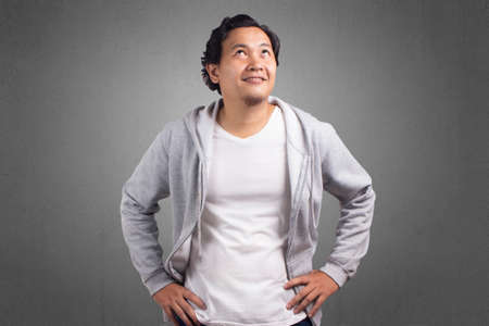 Young Asian man smiling wearing jacket, Eyes glance to the topの写真素材