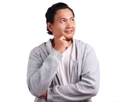 Young Asian man wearing white shirt and gray jacket thinking with a smile expression. Isolated on...
