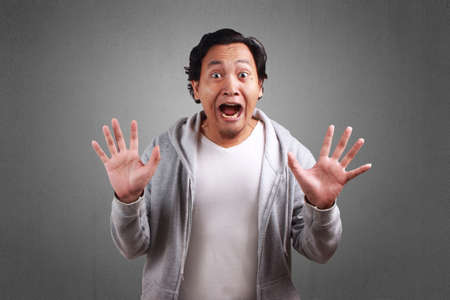 Young asian men wearing a jacket, Shocked With Open Mouth. Both hands above