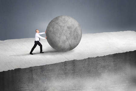 Businessman pushing large stone up to hill , Business heavy tasks and problems conceptの写真素材