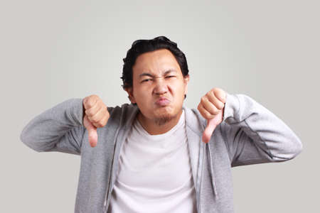 Portrait young asian men wearing jacket upset with thumbs downの写真素材
