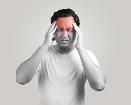Young Asian man wearing white shirt having headache. Monochrome black and white. Close up body...