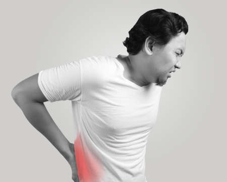 Young Asian man wearing white shirt having lower back pain. Monochrome black and white. Close up...
