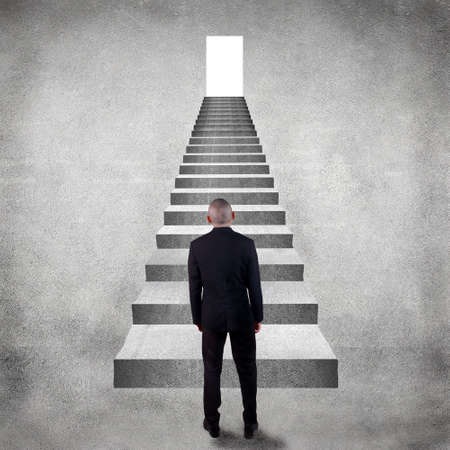 Rear view of a businessman facing high staircase for light door
