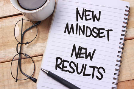 New mindset new results words letter, written on notepad, work desk top view. Motivational self development business typography quotes conceptの写真素材