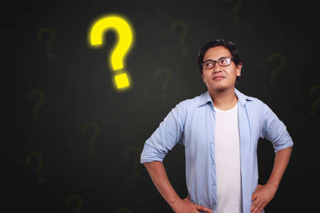 Young Asian man wearing white and blue shirt thinking, curious expression with sign. Close up body...