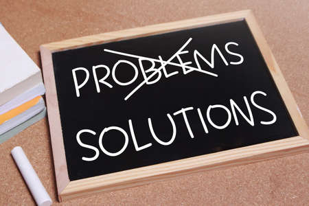 Problems and Solutions words letter, written on blackboard, work desk top view. Motivational...