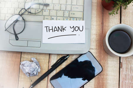Thank You words letter, written on piece of memo paper, work desk top view. Motivational business finance typography quotes conceptの写真素材