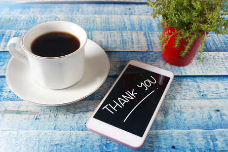 Thank You words letter, written on smart phone screen, work desk top view. Motivational business...