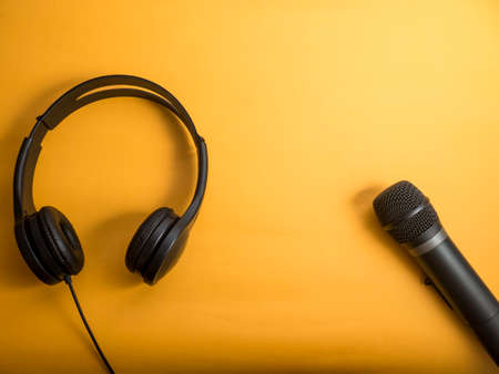 Headphone and microphone. Earphones on orange background. Listening music sound and singing karaoke song conceptの写真素材