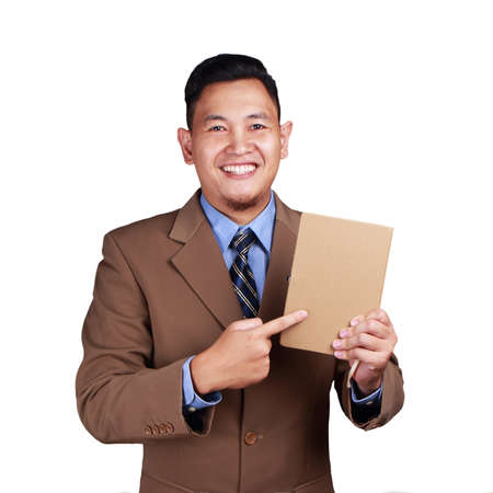 Portrait of young businessman holding and showing a book, empty cover template mock up, isolated on whiteの写真素材