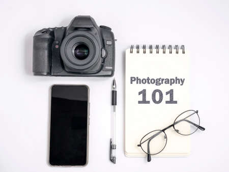 Photography 101 Lesson Concept, Top View Flat Layout Photographer Working Desk. DSLR Camera with smart phone notebook and eyeglassesの写真素材