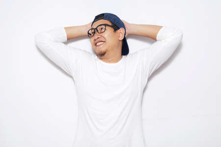 Photo image of young Asian man looked happy, thinking and looking up, hands behind head, having good...