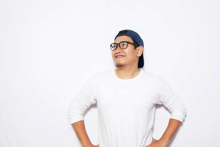 Photo image of young Asian man looked happy, thinking and looking up, having good idea. Half body portrait against white wall with copy spaceの写真素材