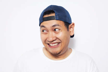 Portrait of funny young Asian man smiling and looking to the side, over white backgroundの写真素材