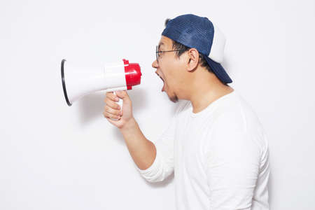 Young Asian sman wearing white shirt shouting with megaphone, angry expression. Close up body...