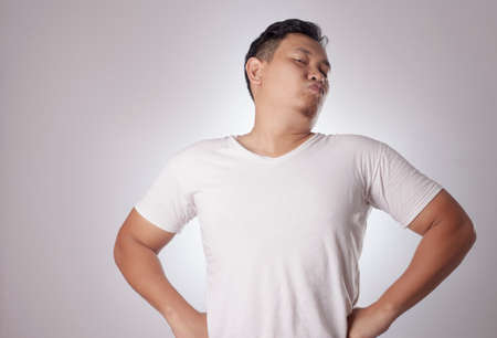 Portrait of funny young Asian man shows his over confidence, hands on hips with arrogant gestureの写真素材