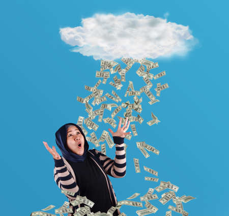 Portrait of happy successful young Asian billionaire woman smiling happily under rain of money. Wealth investment economic conceptの写真素材