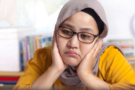 Portrait of Asian muslim businesswoman looking tired sleepy and lazy waiting for bad internet...