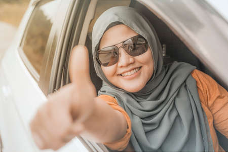 Portrait of Asian muslim lady smiling while drive her car, lifestyle having fun leisure in vacation trip, car ride sharing conceptの写真素材