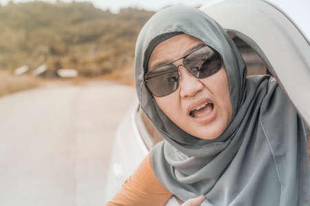 Portrait of Asian muslim lady driver shocked to see something bad in front of her car, accident in the road conceptの写真素材