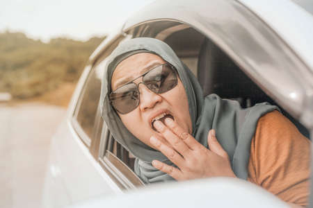 Portrait of Asian muslim lady driver shocked to see something bad in front of her car, accident in the road conceptの写真素材