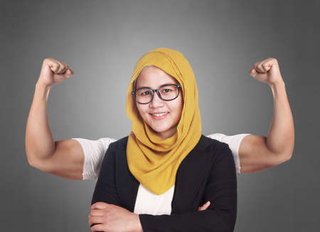 Business power concept. Young Asian muslim businesswoman smiling with strong powerful arms drawn behind. Inner power authorityの写真素材