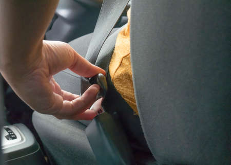 Female driver put on seat belt before driving a car, insurance traffic safety concept