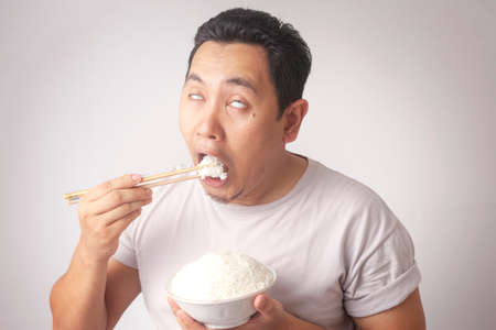 Portrait of good looking Asian young man enjoys a cup of white riceの写真素材