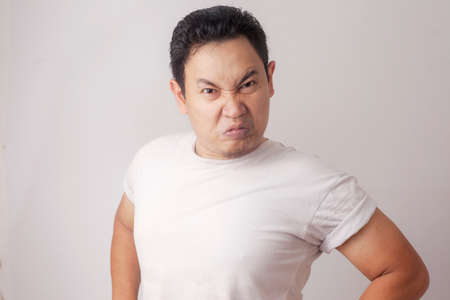 Photo image of funny Asian man showing cynical unhappy angry facial expression