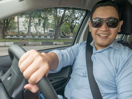 Portrait of young Asian man smiling and driving a car, good looking entrepreneur, car sharing...