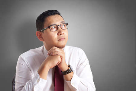 Portrait of Asian businessman wondering something, thinking Gesture, imagine bright future vision...
