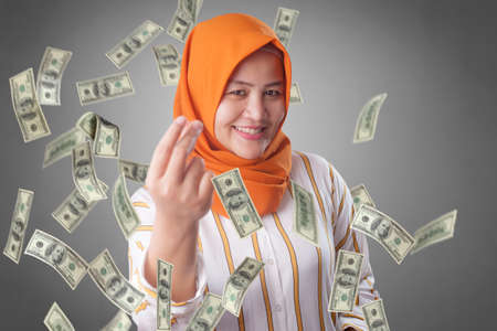 Portrait of happy successful young Asian billionaire muslim woman smiling happily under rain of...