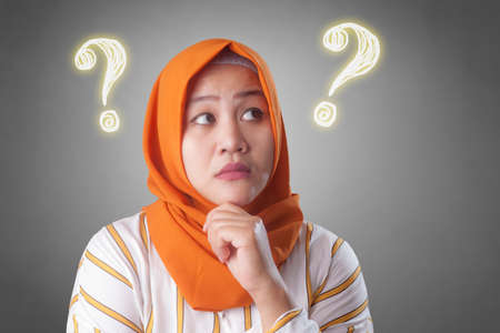 Portrait of Asian muslim woman thinking solution to solve problem, questioning concept with quesion markの写真素材