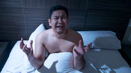 Portrait od Asian man depressed frustrated and hard to sleep on the bed in the midnightの写真素材