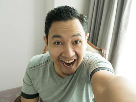Portrait of happy funny Asian man laughing at camera, happiness joyful concept, man taking selfie...