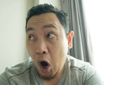 Photo image of young funny Asian man shocked or surprised expression with mouth open