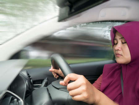 Female Asian muslim driver sleeping while driving a car, dangerous traffic safety accident crash car...
